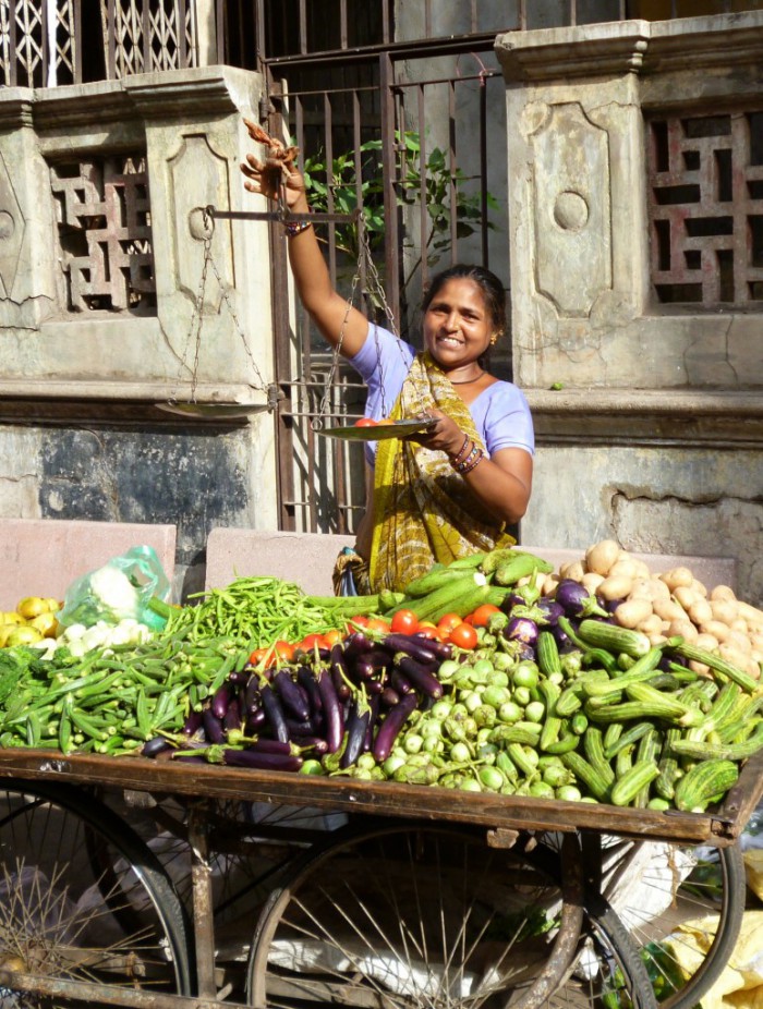 Vegetable vendor weighing produce on a hand balance